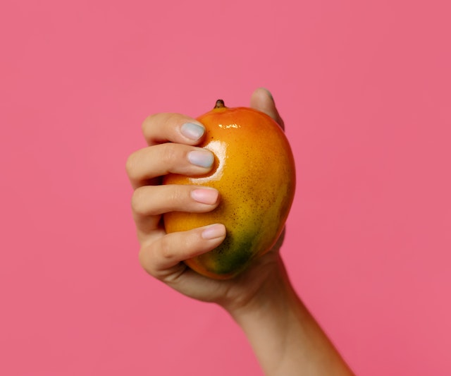 A person holdng one mango in their hand (Is Mango Good For Weight Loss?)