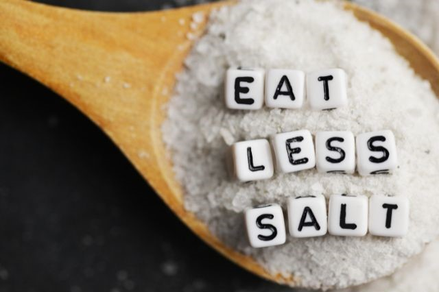 A text saying eat less salt written on a spoon full of salt