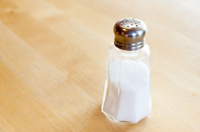 a bottle of table salt laying on a wooden surface