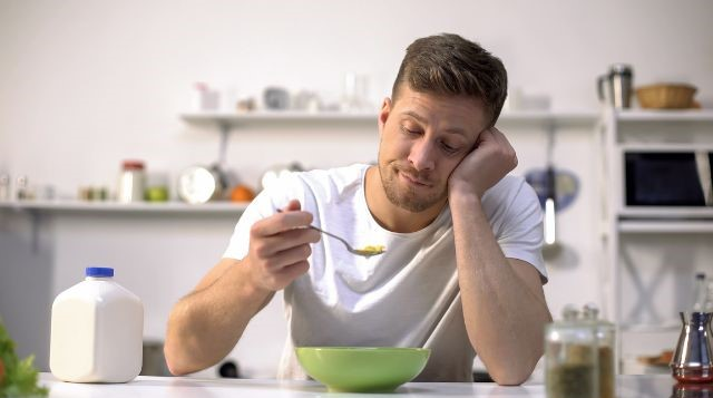a man looking at his spoon while eating