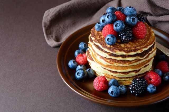 a plate full of pancakes with blueberries and strawberries
