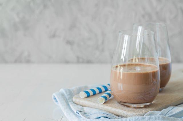 Two glasses of chocolate milk laying on a white surface (Is Chocolate Milk Good For Weight Loss)