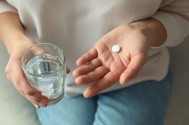 a woman holding a pill and glass of water
