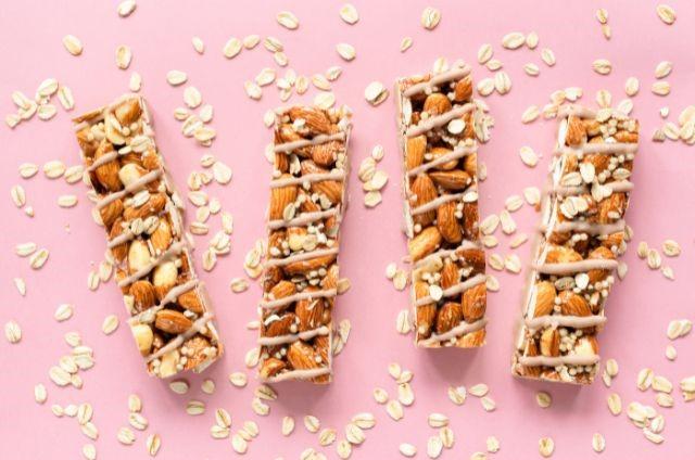 three pieces of granola and nuts on a pink surface (Are Protein Bars Good for Weight Loss?)