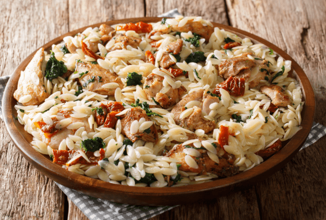 A dish of chicken and sun-dried tomato orzo with herbs.
