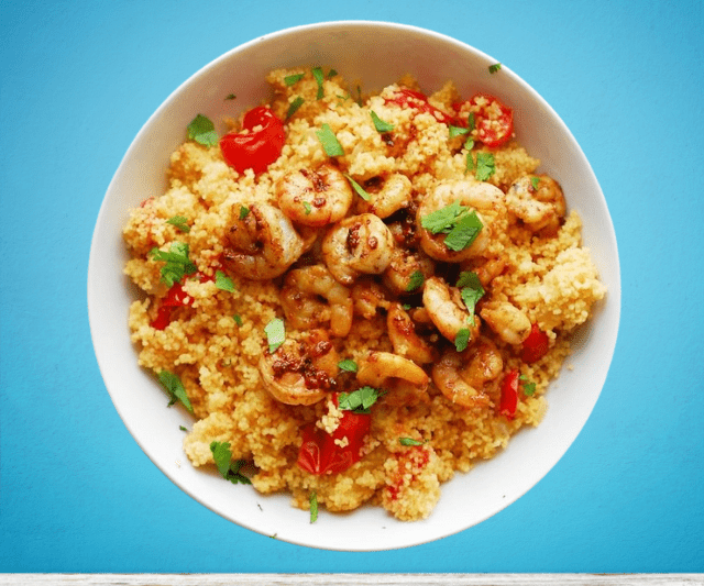A bowl of spicy shrimp served over couscous and vegetables.