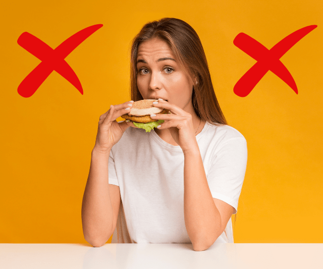 A woman eating a burger with a worried expression, with two red X marks in the background, highlighting the potential pitfalls of cheat meals.